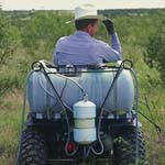Farmer riding ATV spray rig